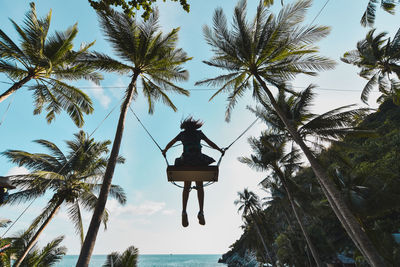 Low angle view of coconut palm tree by sea against sky