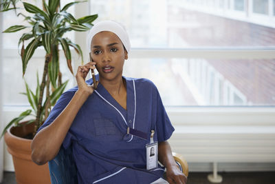 Young female doctor talking on phone at work