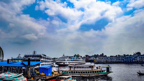 Boats moored at harbor against sky