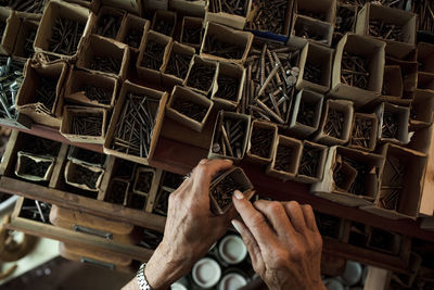 Directly above view of senior saleswoman removing nails from cardboard box in hardware store