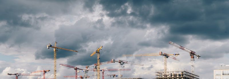 Low angle view of cranes against sky