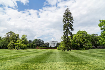 Grassy field with white house in background