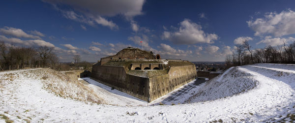 Panoramic view of dam on snow covered land against sky