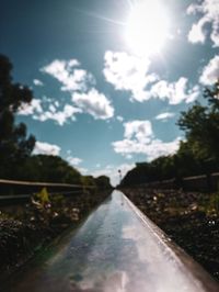 Road amidst trees against sky on sunny day