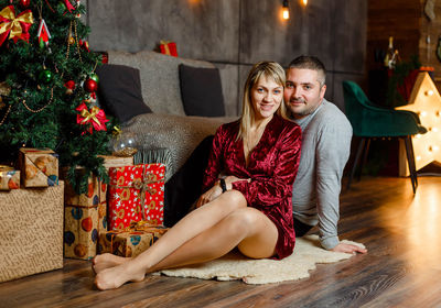 Beautiful couple hugging near christmas tree on blurred background