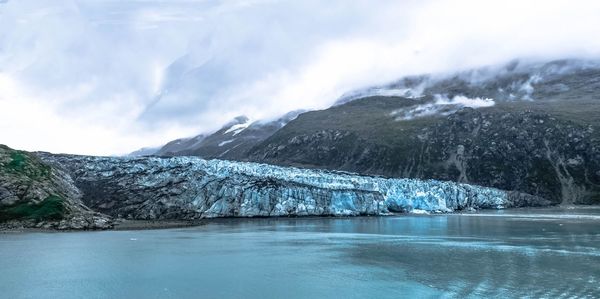 Lake by glaciers against sky