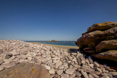 Rocks on beach against clear blue sky