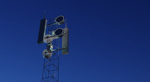 Low angle view of telephone pole against clear blue sky