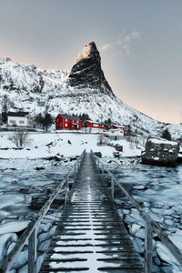 Footbridge over frozen lake against snowcapped mountains