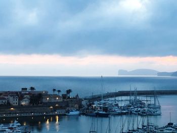 Boats moored at harbor against sky at dusk