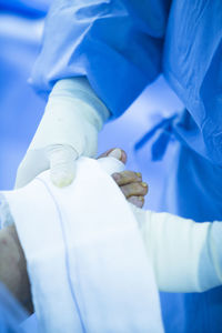 Midsection of surgeon wrapping bandage on patient wound in operating room