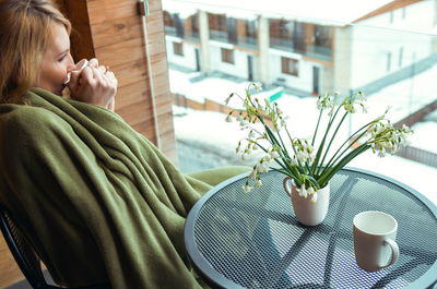 Midsection of woman with coffee cup on table at home