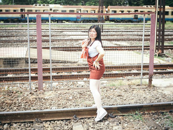 Portrait of a smiling young woman standing on railroad track