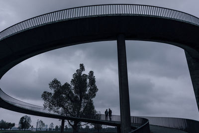 Two businessmen standing on dark bridge, having a meeting