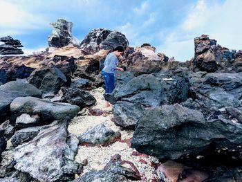 Rear view of man standing on rock against sky