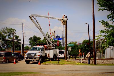 Worker in truck buckets near pole