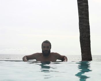 Portrait of man in infinity pool against sky