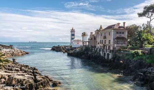 Lighthouse by sea against sky