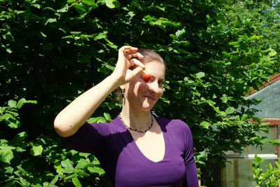 Young woman standing against plants