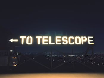 Text on illuminated sign in city at night