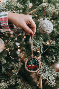 Cropped hand of woman decorating christmas tree