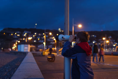 Rear view of man walking on road at night