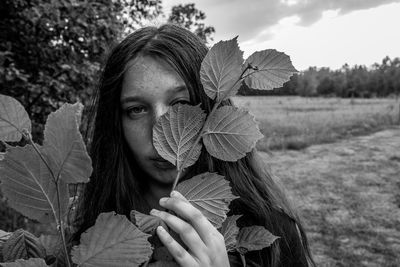 Portrait of teenage girl holding plant stem