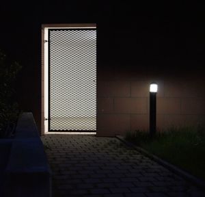 Empty road by illuminated building against sky at night