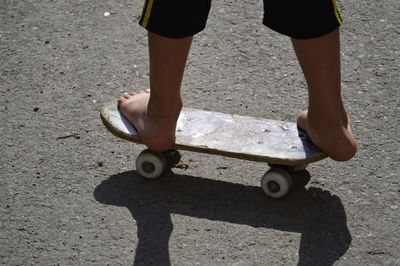 Low section of boy skateboarding on road