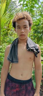 Portrait of young woman standing against plants