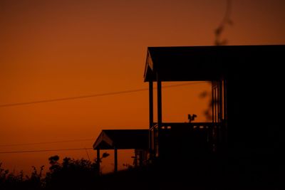 Silhouette house against orange sky during sunset