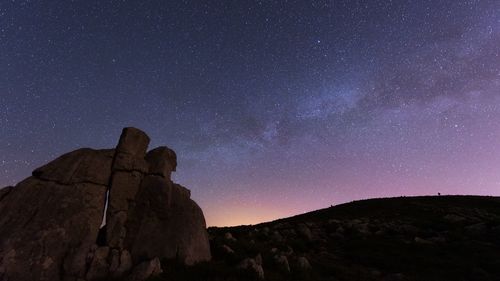 Low angle view of rocks against star field sky at night