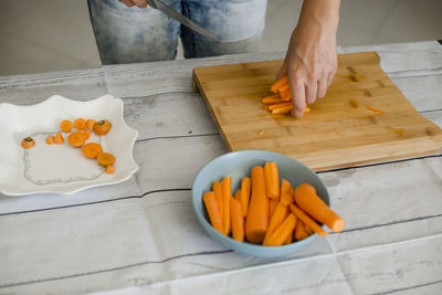 Midsection of woman cutting carrot on board