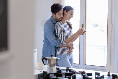 Young couple standing against window