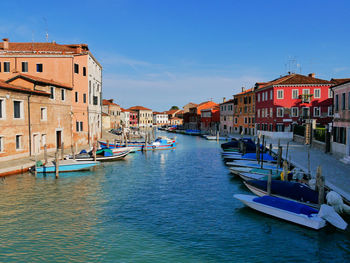 Boats moored in canal by buildings in city