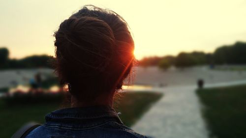 Rear view of woman against river during sunset