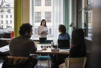 Businesswoman discussing with creative people in meeting at modern office