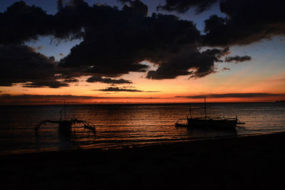 Silhouette boat moored on sea against sky during sunset