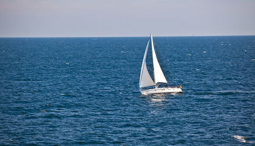 Sailboat sailing on sea against clear sky