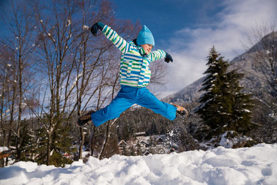 Full length of boy jumping in snow