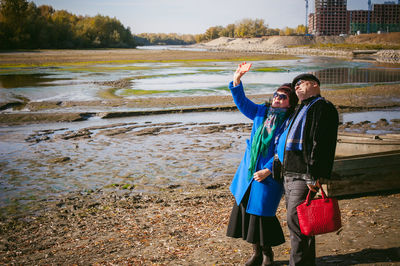 Mature couple taking selfie with mobile phone while standing on field