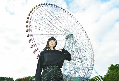 Low angle view of woman with ferris wheel against sky