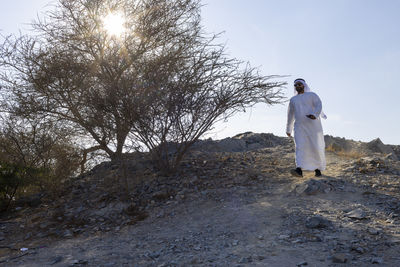 Man wearing traditional clothing walking on land against clear sky