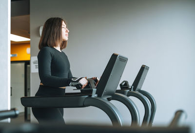 Young fitness brunette woman training for cardio equipment treadmill at gym