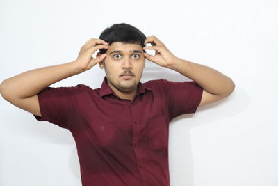 Portrait of young man standing against white background