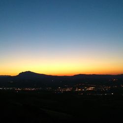 Illuminated cityscape against sky at sunset