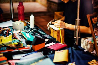 Midsection of woman holding container by messy table at home