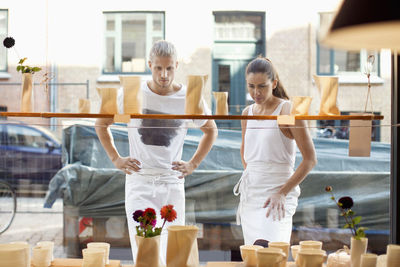 Workers looking at displayed crockeries in workshop from outside