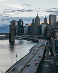 Brooklyn bridge over river by city against sky