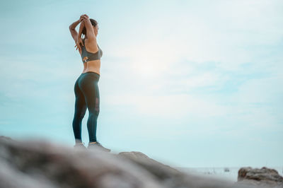 Full length of woman standing at beach against sky